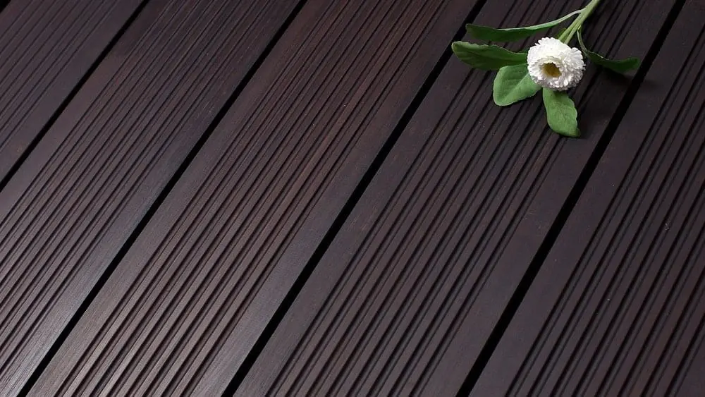 Primer plano de suelo de bambú oscuro con una flor encima.